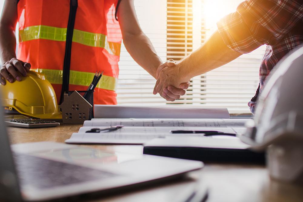 Two people shaking hands on a job site.